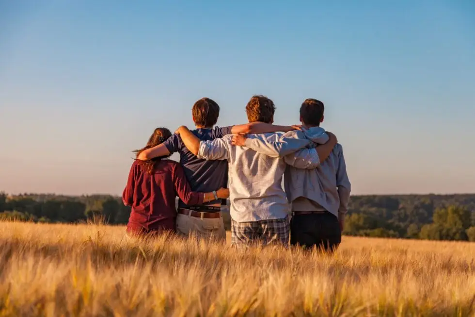 Auf diesem Bild ist eine Familie zu sehen. Die Menschen halten sich an den Armen. Sie befinden sich auf einem Feld und beobachten den Himmel.