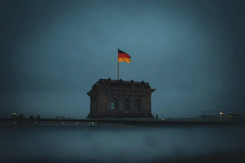 Auf diesem Bild ist eine deutsche Fahne auf einem Gebäude zu sehen. Der Himmel im Hintergrund ist dunkelblau