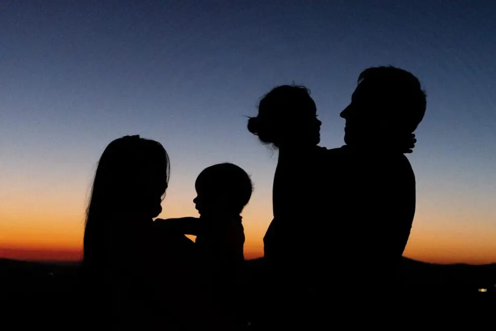 Auf diesem Bild ist der Schatten einer Familie zu sehen. Die Familie guckt auf einen Sonnenuntergang