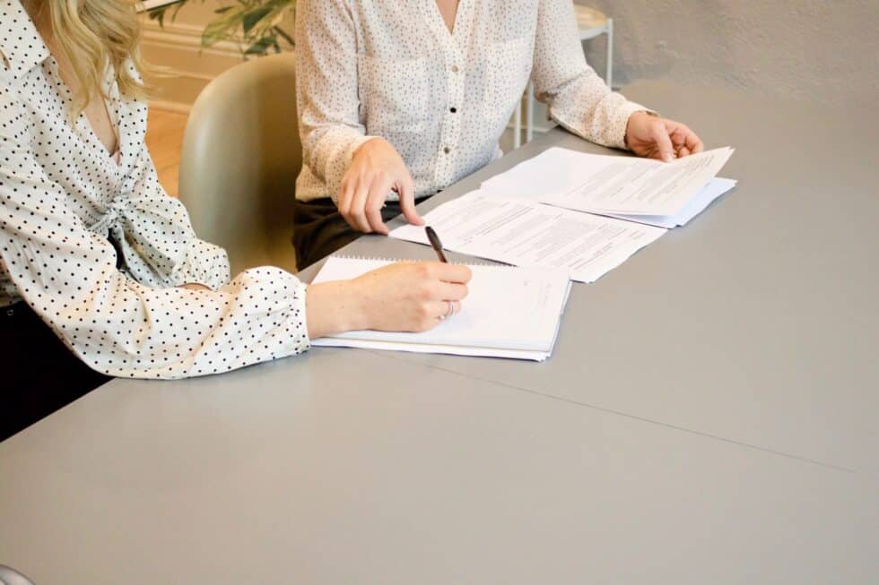 This picture shows a woman signing a document at a lawyer's office.