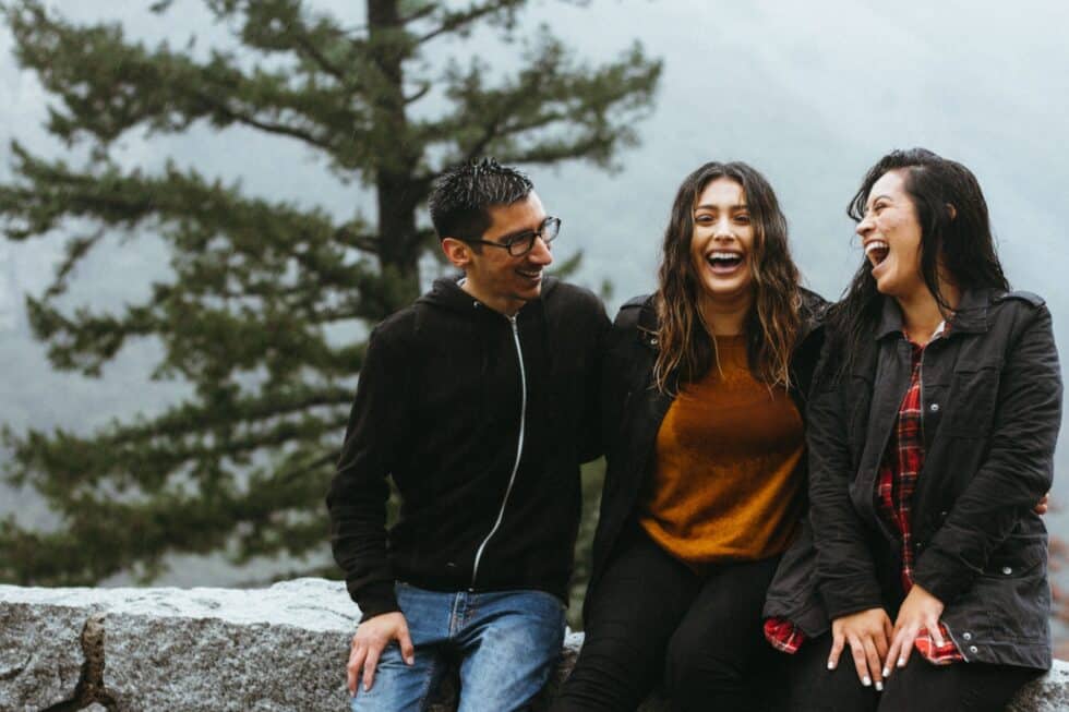 In this picture you can see friends (two women and a man) laughing together.