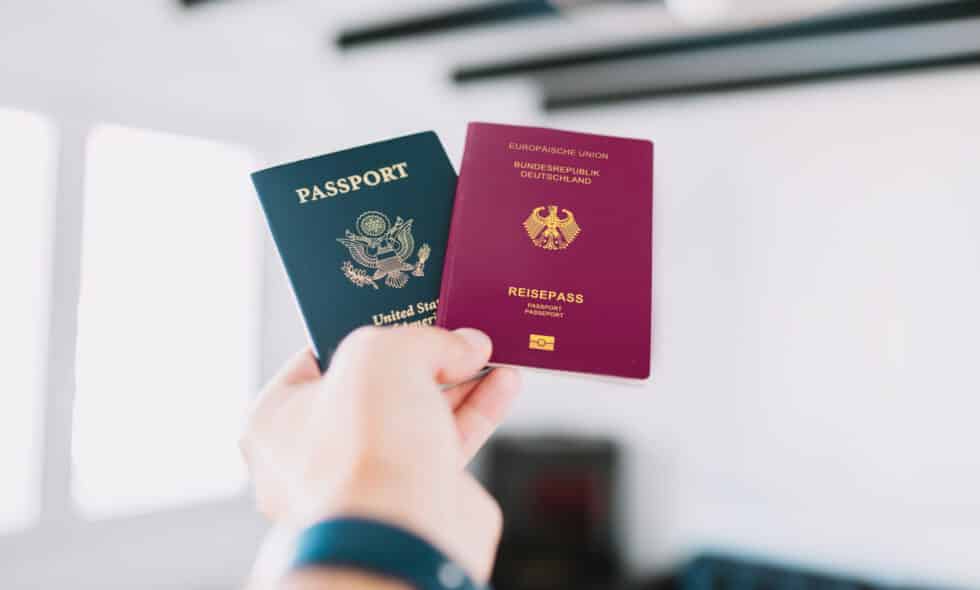 In this picture, a German and American passport is held in one person's hand.