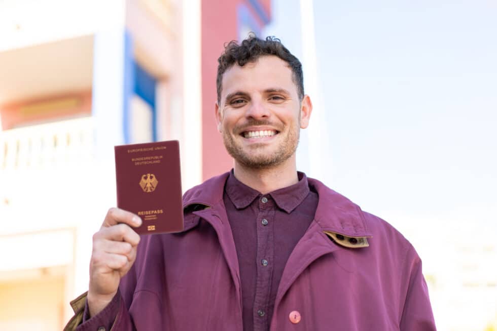 在这张照片中，您可以看到一位手持护照的年轻人面带微笑。根据计划中的新入籍法，5 年后即可入籍