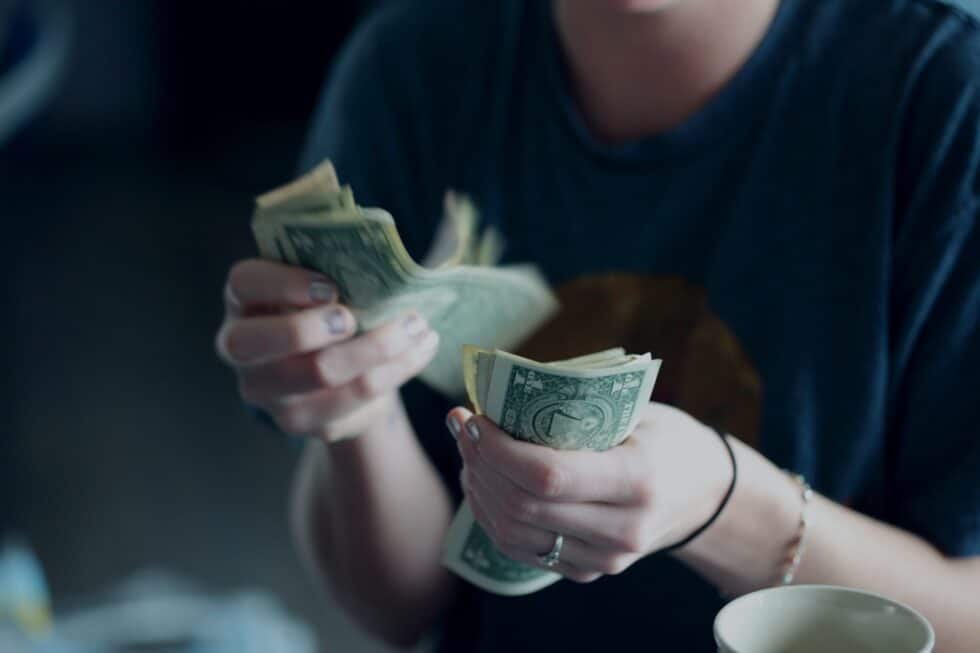 In this photo you can see a woman counting up money. The money are American dollar bills