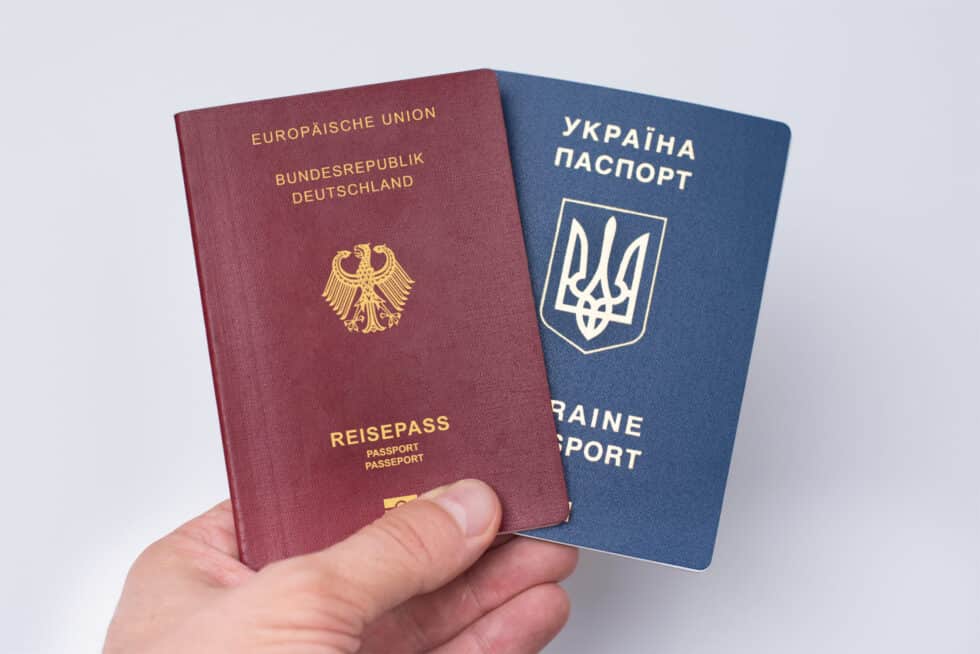 This photo shows a Ukrainian and German passport. The passports are held in one hand