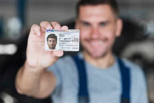 На этой фотографии мужчина держит в руке карточку с видом на жительство 104c AufenthG и улыбается.