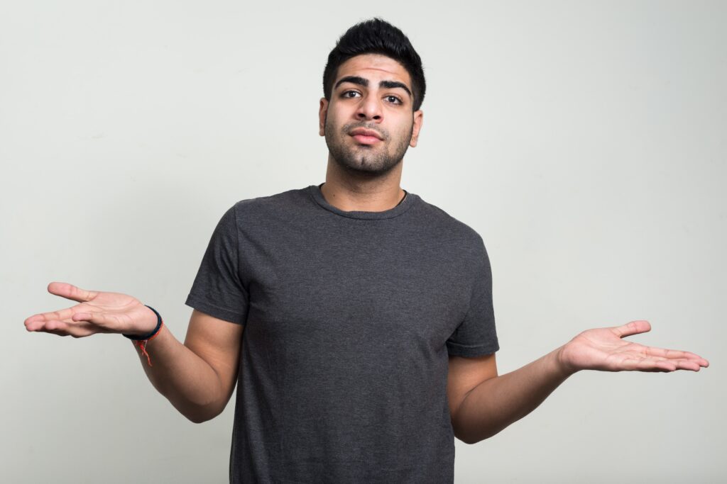 رجل أجنبي شاب حسن المظهر يقف أمام خلفية بيضاء ويرفع كلتا يديه بشكل متردد كما لو كان يطرح سؤالاً أو يطلب النصيحة. وهو يرتدي قميصاً رمادي اللون وينظر إلى الكاميرا بتعبير مثير للتساؤل قليلاً. يمكن أن يمثل ذلك حالة رجل يتأمل في تعقيدات قضايا مثل &quot;الترحيل رغم عرض العمل&quot;.