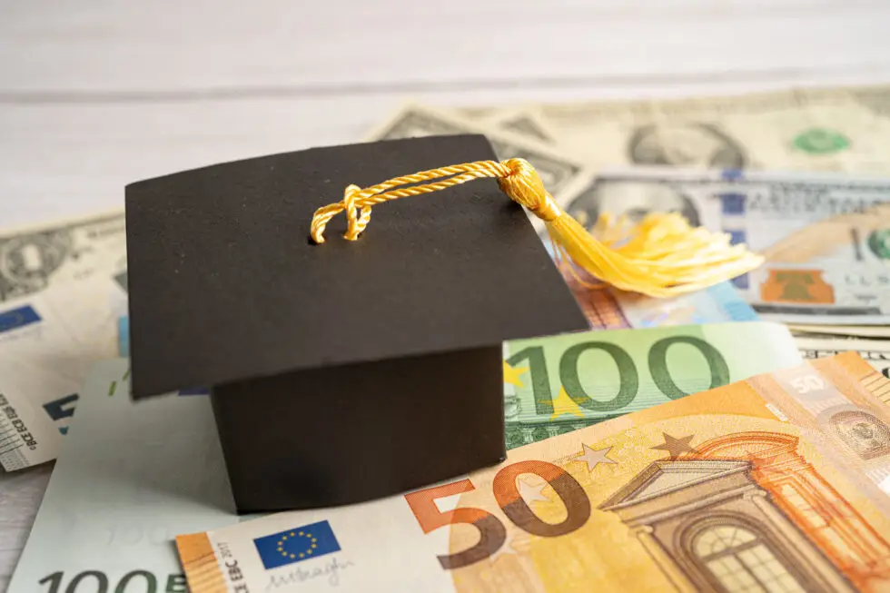 Ein Doktorhut liegt auf mehreren Euro- und Dollarnoten und symbolisiert die Verbindung zwischen Bildung und finanzieller Unterstützung. Diese Darstellung zeigt die Bedeutung von Förderprogrammen wie Bafög für Studierende, die einen Antrag auf Bafög stellen, um die Kosten ihres Studiums zu decken.