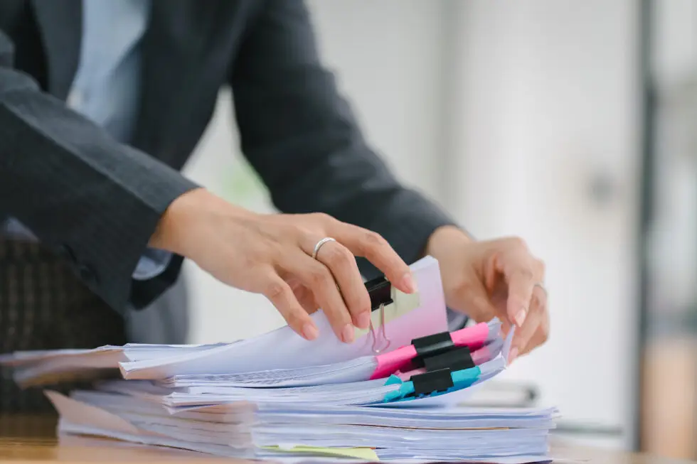 Les mains d'une personne triant des documents volumineux - symbolise le processus détaillé de soumission des documents pour la naturalisation en Allemagne en 2024. L'image représente la préparation et l'organisation minutieuses des documents nécessaires pour demander la citoyenneté allemande.