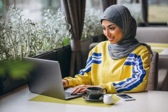 Eine Junge Frau mit Hijab beantragt online ihre Meldebescheinigung für das Einbürgerungsverfahren in Deutschland.