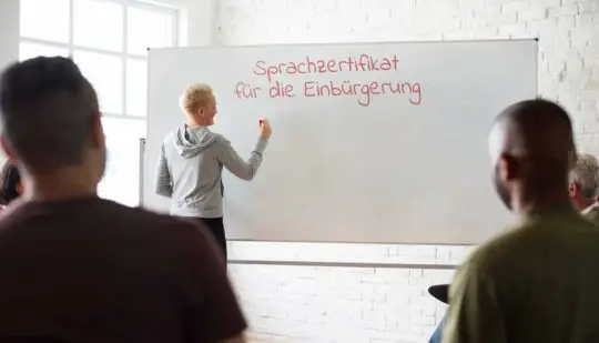 Bei der Vorbereitung auf die Antragstellung zum deutschen Pass ist die Frage wichtig welches Sprachzertifikat für die Einbürgerung passt. Eine Sprachlehrerin schreibt das Thema auf die Tafel