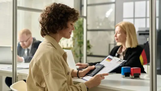 Eine Frau sitzt an einem Schalter. Sie hat die Schwierigkeit, dass ihr Antrag auf Einbürgerung abgelehnt wurde