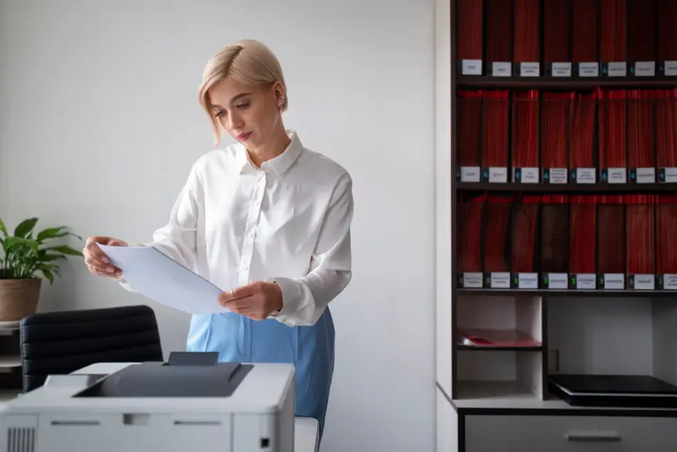 Sur cette photo, vous voyez une femme dans un bureau, des dossiers à la main. Une image symbolique de la durée nécessaire pour demander un passeport allemand