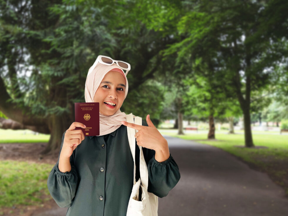 Uma mulher com um lenço na cabeça e um passaporte alemão na mão. Símbolo para o tema dos requisitos para o passaporte alemão