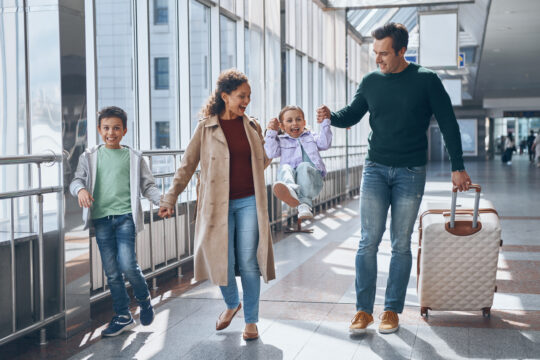 Auf diesem Bild sehen Sie eine glückliche Familie zusammen am Flughafen als Symbol für das Visum zur Familienzusammenführung, auch nationales Visum genannt