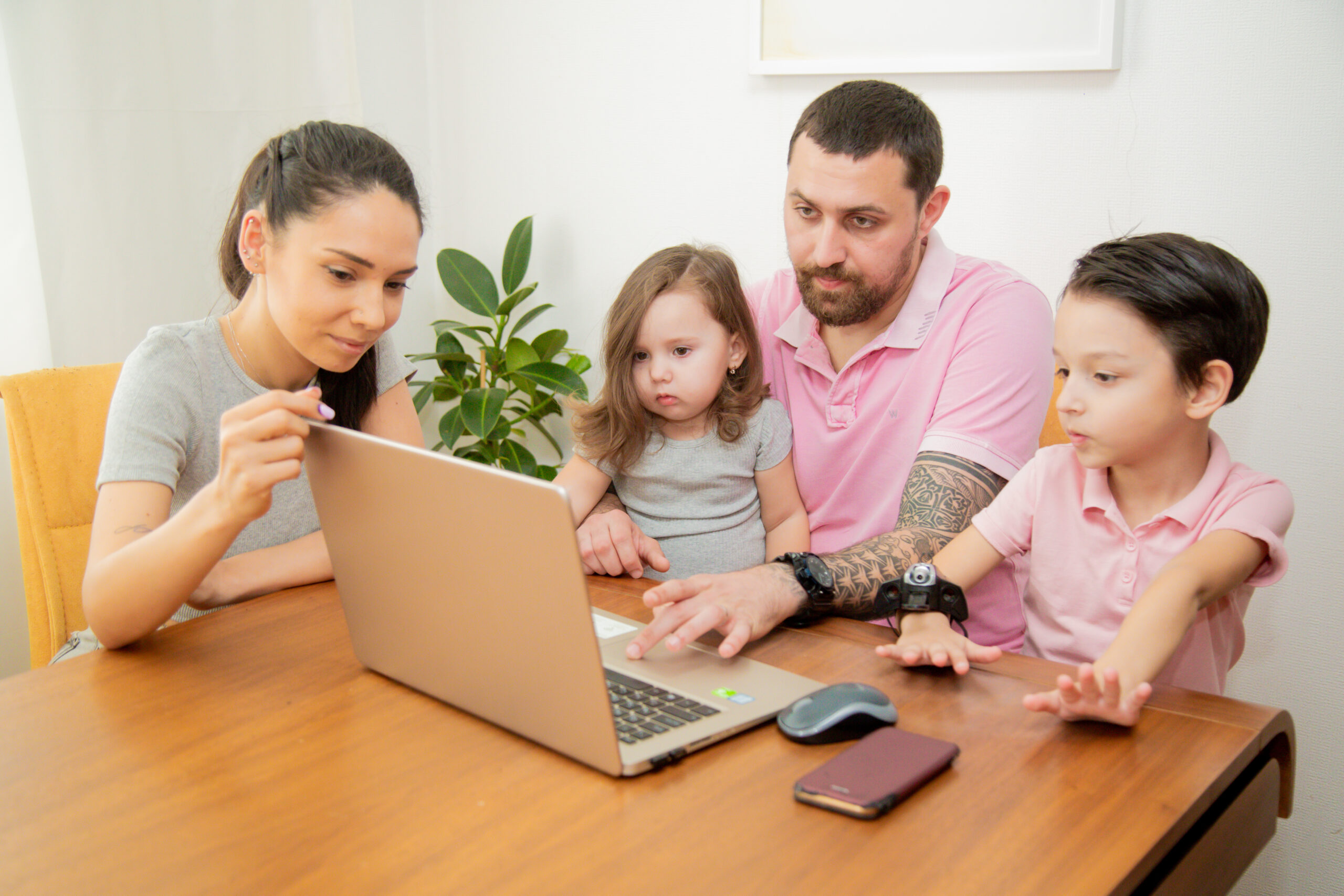 Eine Familie sitzt am Laptop. Der Vater recherchiert zum Thema Familienzusammenführung Ausländerbehörde und welche Aufgaben die Ausländerbehörde bei der Familienzusammenführung hat