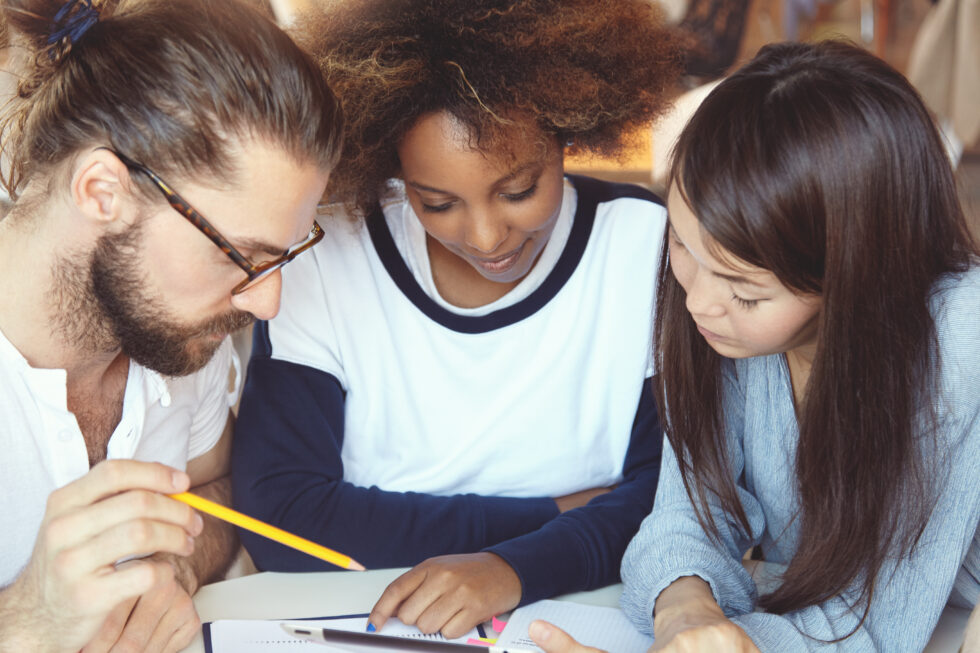 In this photo you can see three people learning together. Symbol for the question: Can you apply for Naturalization with A2?