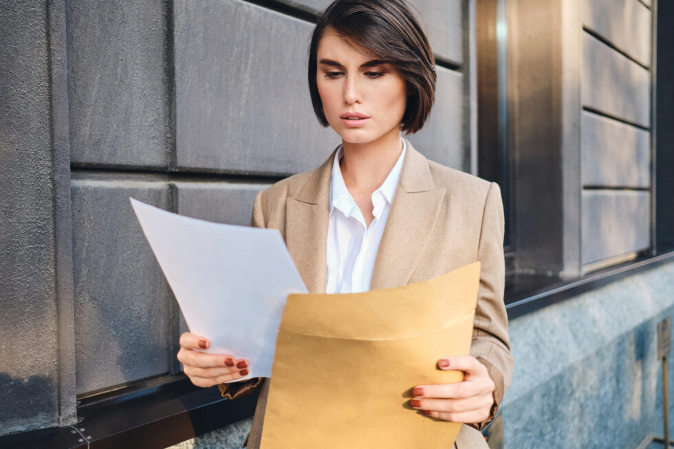 A woman looks at a sheet with an envelope she has opened. Symbol on the subject of pre-consent Foreigners' office family reunification