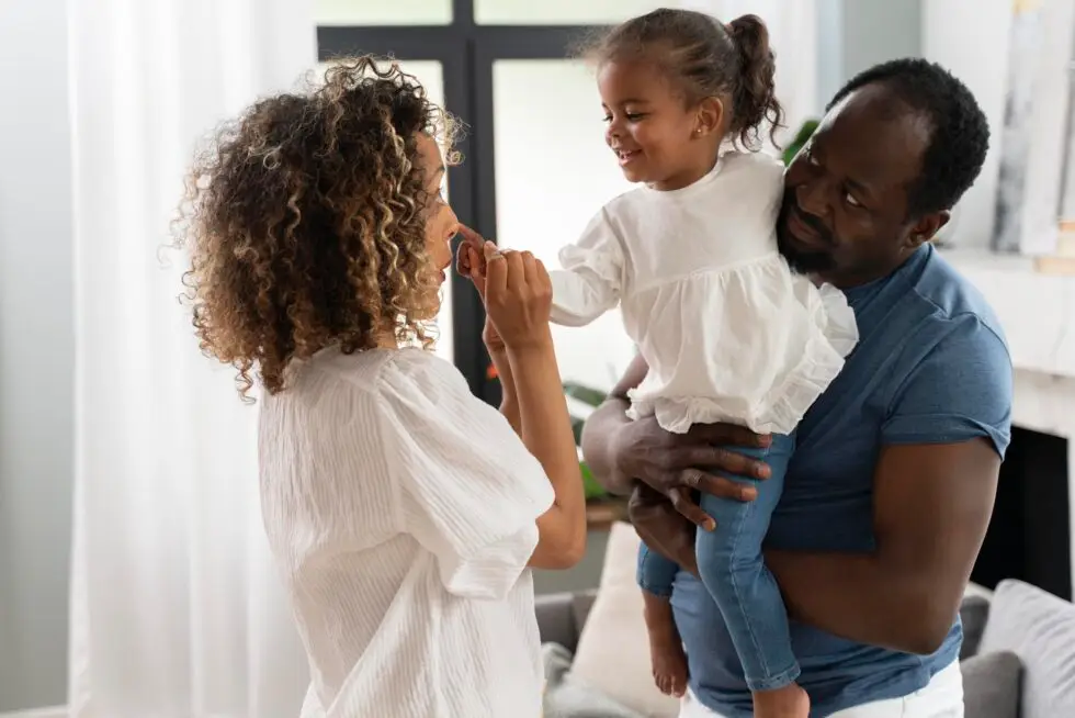 Zwei Eltern mit ihrem Kind. Der Vater hat das Kind im Arm. Symbolbild zum Thema Familiennachzug Voraussetzungen