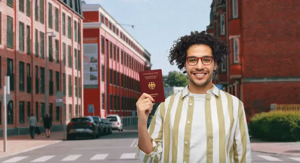Ein Mann hat einen deutschen Pass in der Hand und lächelt. Symbol für das Thema; Deutsche Staatsangehörigkeit