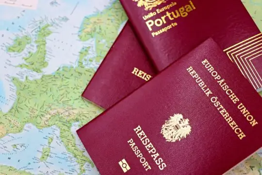 Das Bild zeigt den österreichischen Pass sowie den Pass von Portugal auf einer Karte von Europa liegend. Ein Ukrainer in Österreich verlor seine Einbürgerung weil er sich weigerte, die Nationalhymne mitzusingen. Wäre das auch in Deutschland denkbar?
