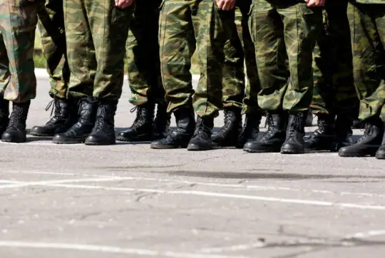 Das Bild zeigt die Beine von Bundeswehrsoldaten in Uniform, die Haltung angenommen haben. Nach Vorschlag eines CDU-Abgeordneten, soll es Migranten in Deutschland ermöglicht werden, die deutsche Staatsbürgerschaft zu erhalten, wenn sie ein Jahr Wehrdienst ableisten. Doch so einfach umzusetzen ist das rechtlich nicht.