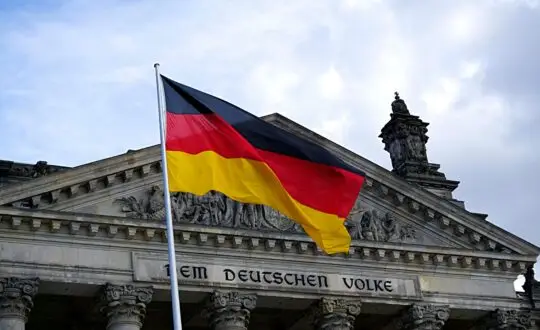 Das Bild zeigt die deutsche Flagge vor dem Reichstagsgebäude in Berlin. Aus für die Turbo-Einbürgerung? Schon im Oktober könnte die Entscheidung fallen. die die Einbürgerung nach drei Jahren streicht.
