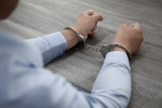 تُظهر الصورة بشكل رمزي شخصًا مقيد اليدين بالأصفاد. ويوضح حكم قضائي صدر مؤخرًا: متى يمكن أن تحول الجرائم الجنائية دون الحصول على الحماية التكميلية؟